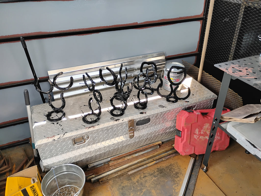 "Freshly painted handmade horseshoe jewelry holders and picture frames drying in the truck art studio — handcrafted Western Christian wall art studio"