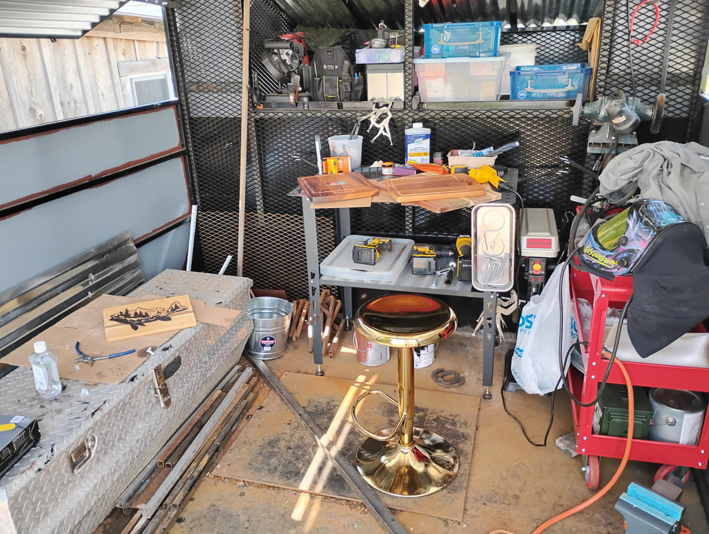 "Inside view of a handcrafted Christian mobile art studio built on a farm truck bed, with workbench, wood-burning tools, welding equipment, horseshoe and wood burning art in progress"