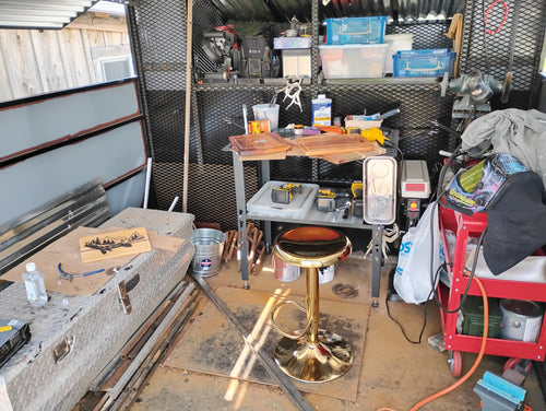 "Inside view of a handcrafted Christian mobile art studio built on a farm truck bed, with workbench, wood-burning tools, welding equipment, horseshoe and wood burning art in progress"